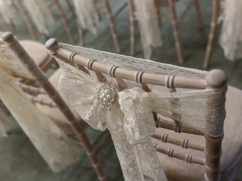 Wedding day set up at The Petwood Hotel. Close up of lace chair sashes ties in a big bow