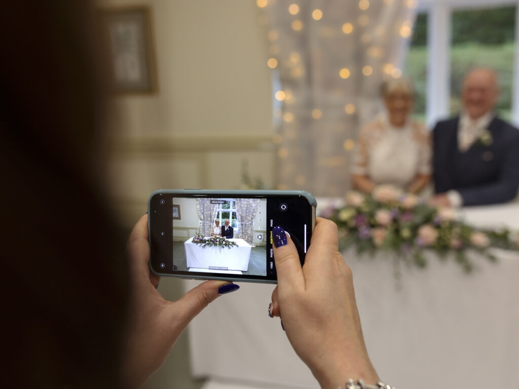 A guest is taking photos of the newlyweds on her phone