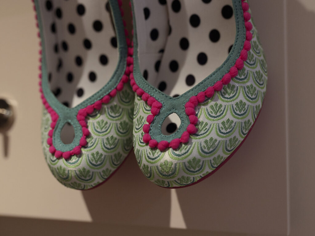 Irregular choice shoes hanging on a rail on the wall. Close up shot of the peep toe design and colourful pattern