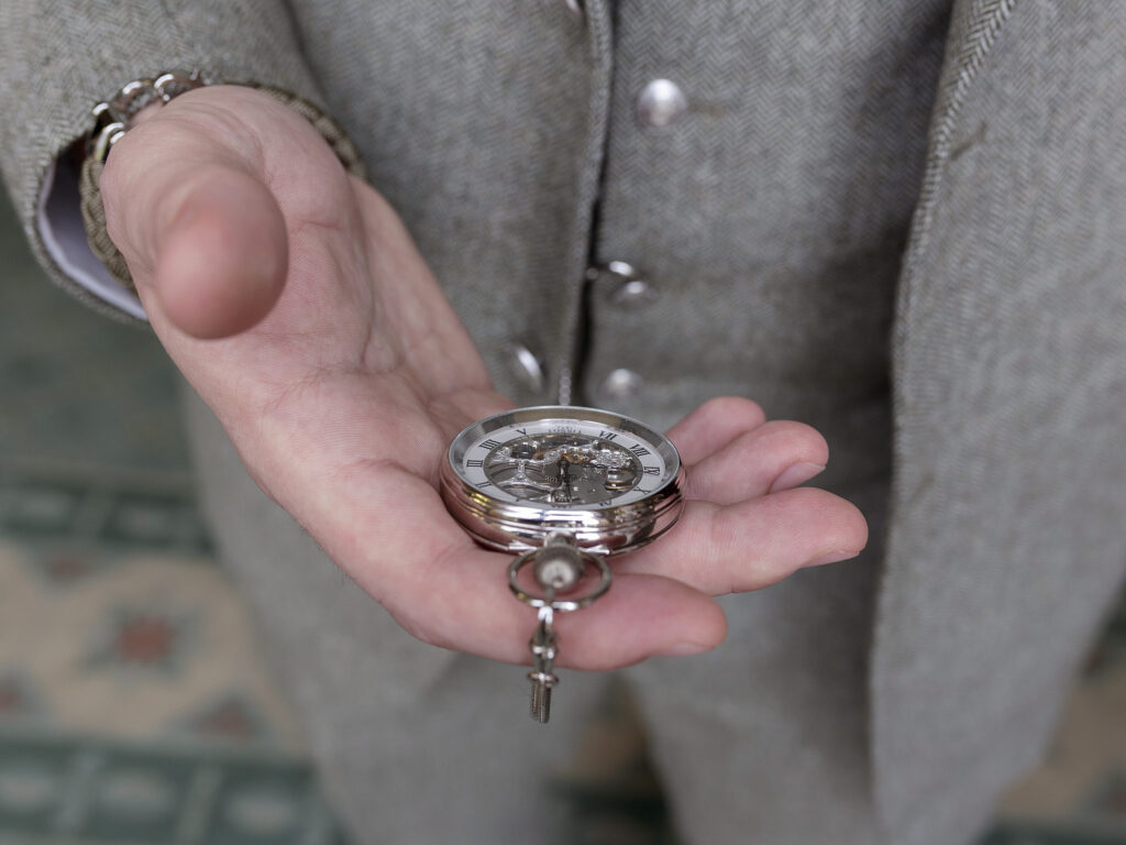Close up of the grooms hand. In his hand is his wedding pocket watch