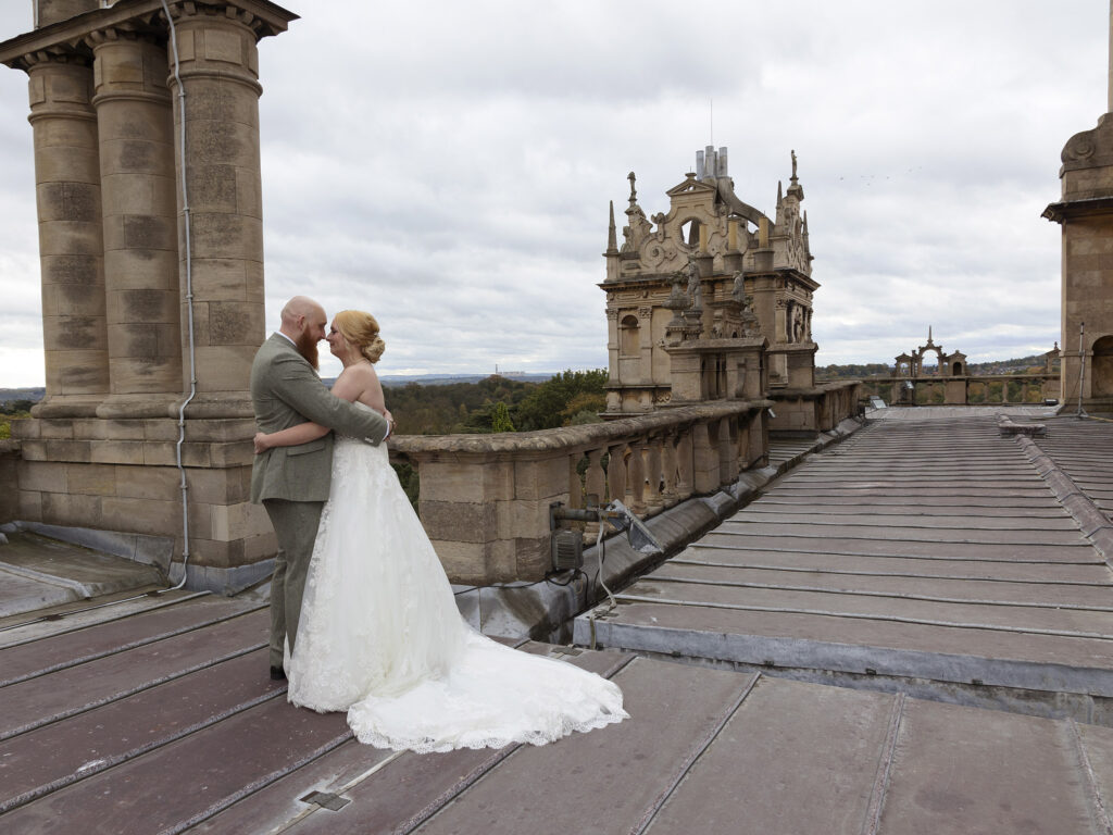 Rooftop of Wollaton Hall. The bride and groom are hugging and have their faces close to each others.