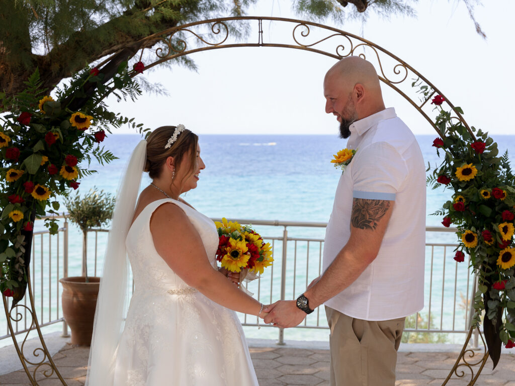 Bride and groom facing each other on the cliff top over looking the sea